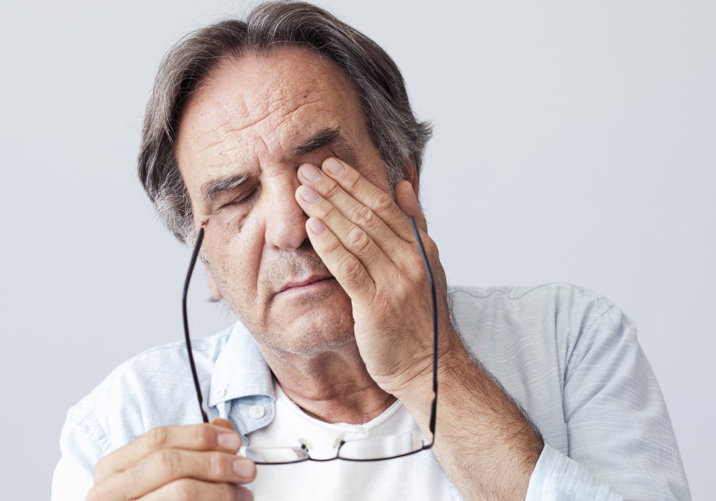 removing reading glasses and rubbing eye with Blepharitis