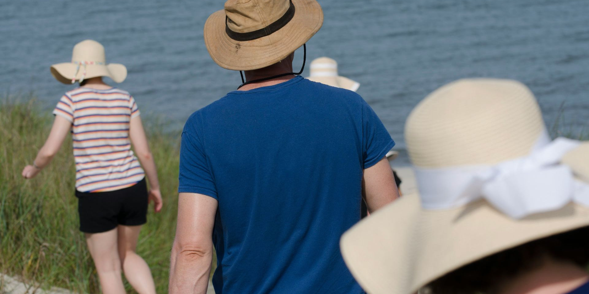 people walking in the sun in cotton clothing & sunhats to help keep sensitive skin cool 