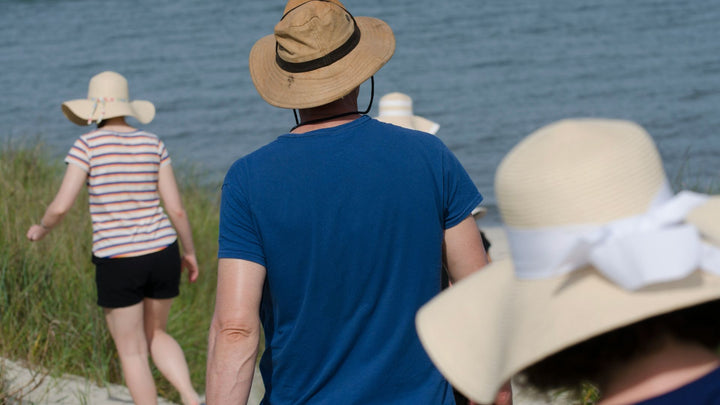 people walking in the sun in cotton clothing & sunhats to help keep sensitive skin cool 