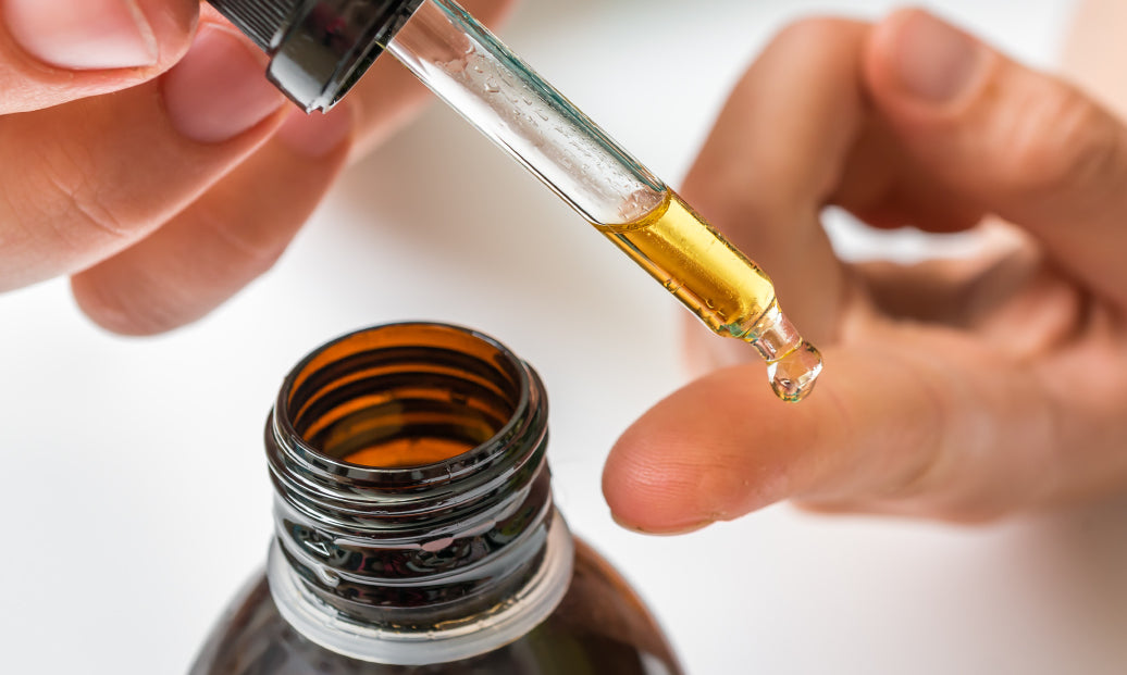 dropping some oil onto a finger from a bottle using a pipette