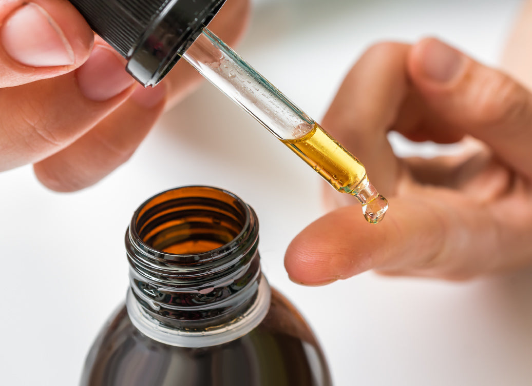 dropping some oil onto a finger from a bottle using a pipette