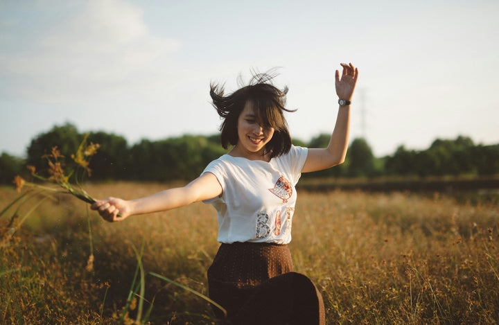 young woman dancing joyfully in a spring field